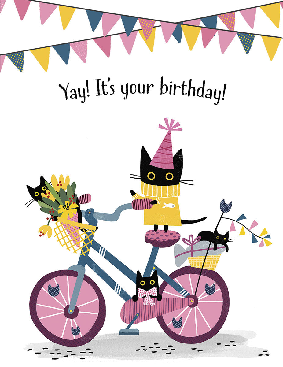 Front of a cute birthday card featuring several black cats on a festive bicycle, adorned with colorful bunting flags, flowers, and party hats. Text reads 'Yay! It's your birthday!'. Ideal for a child's celebration.