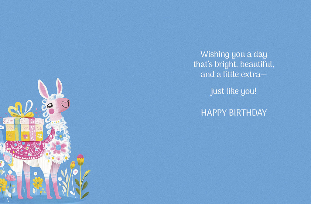 Inside view of the cute llama birthday card. The left side shows the pink and white llama with a gift box and flowers. The right side features a heartfelt message in elegant script: "Wishing you a day that's bright, beautiful, and a little extra—just like you! HAPPY BIRTHDAY" on a solid blue background.