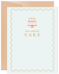Elegant birthday greeting card featuring a pink and gold cake illustration with text 'this calls for CAKE' on a light blue background with a gold wavy border, accompanied by a kraft envelope.