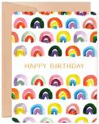 Vibrant watercolor rainbow patterned greeting card with 'HAPPY BIRTHDAY' in gold text on the front, next to a kraft envelope.