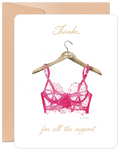 Funny greeting card for her, featuring a watercolor illustration of a pink bra on a wooden hanger with 'Thanks... for all the support' text in gold script, perfect for a supportive woman or bestie.