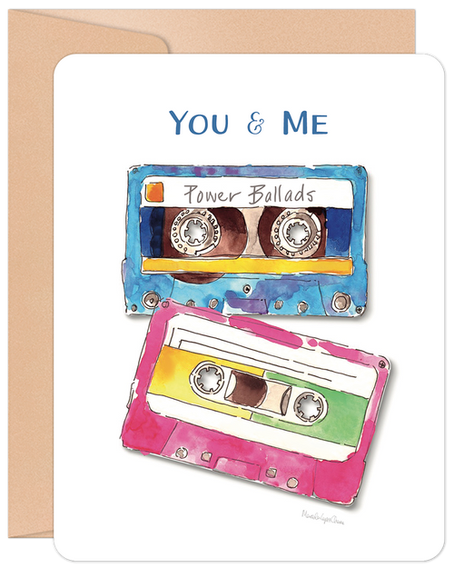 Anniversary greeting card featuring two watercolor-style retro cassette tapes, one blue labeled 'Power Ballads' and one pink/yellow, with 'YOU & ME' text at the top, on a white background with a brown envelope.