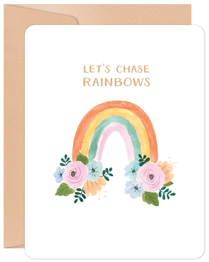 White greeting card with a watercolor rainbow and pink and blue flowers, text 'LET'S CHASE RAINBOWS', and a kraft envelope.
