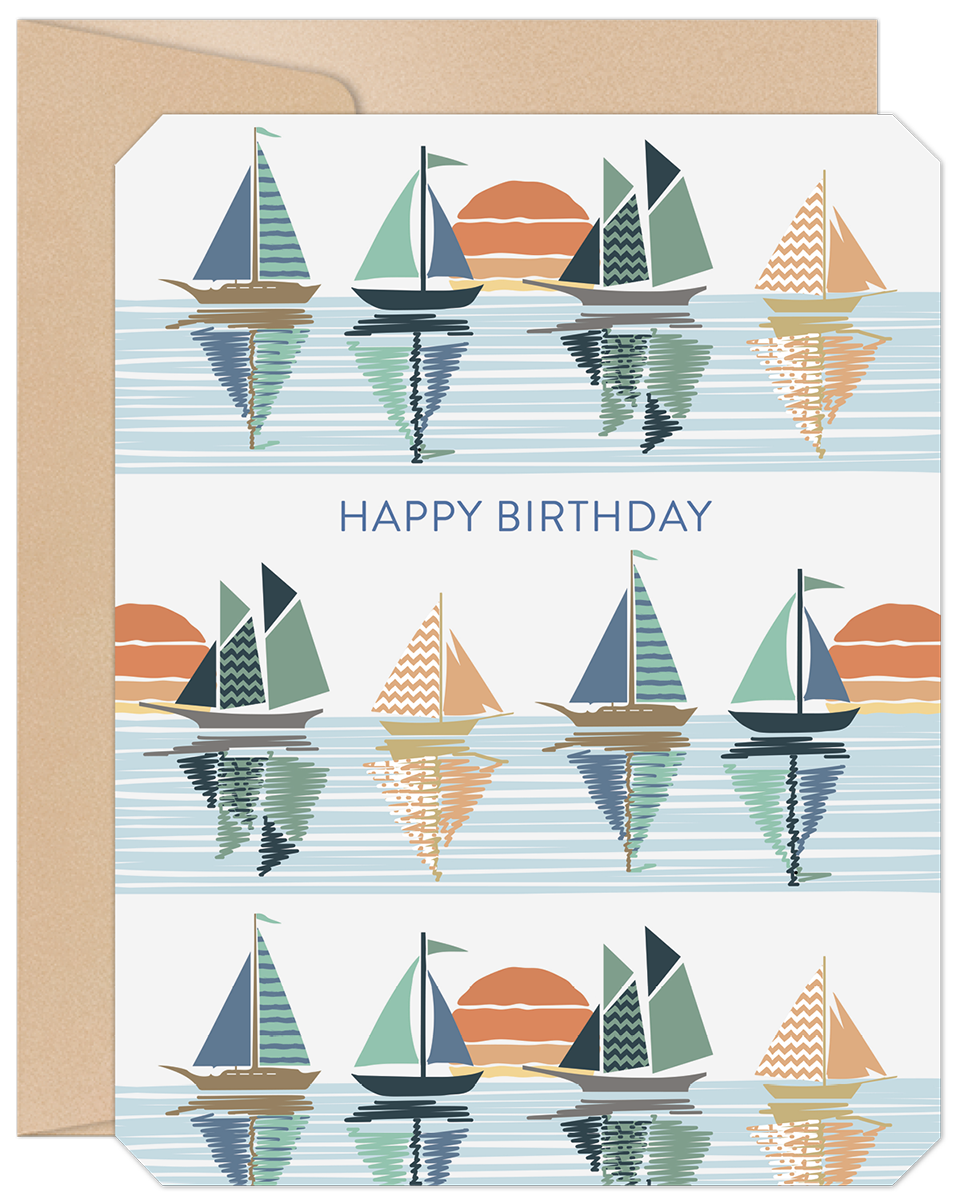 Front view of a lighthearted birthday greeting card featuring a repeating pattern of colorful sailboats on reflective blue water with orange sunsets, accompanied by a kraft paper envelope.