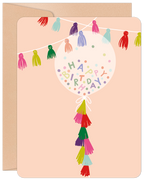 Vibrant birthday greeting card featuring a clear balloon filled with 'Happy Birthday' confetti, colorful tassels, and a string of festive bunting on a blush pink background, perfect for any celebration.
