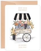 Watercolor illustration greeting card featuring a charming flower cart with vibrant pink, orange, and yellow blooms under a black and white striped awning. Elegant text reads 'HOPE YOUR BIRTHDAY IS LOVELY (LIKE YOU)'. Perfect floral card for a special celebration.