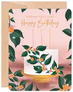 Elegant botanical birthday greeting card featuring a white cake with green leaves and orange berries, three candles, on a soft pink background with a kraft envelope. Perfect for a parent.