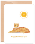 Greeting card featuring a stylized orange tiger lying under a bright yellow sun, with the cheerful message 'happy birthday, tiger' on a white background, partially revealing a kraft envelope.