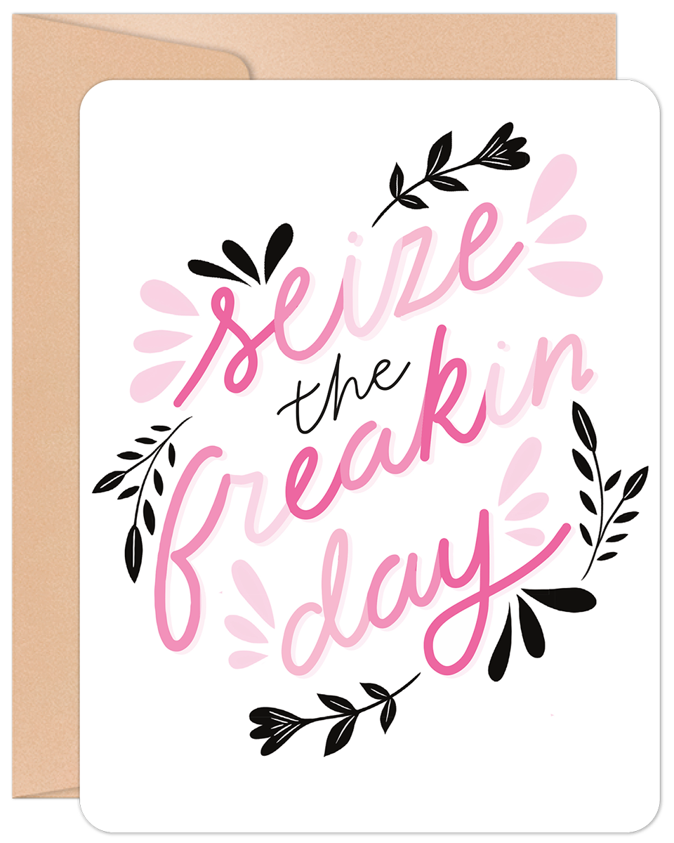 Encouraging greeting card for a friend, featuring vibrant pink script 'Seize the freakin' day' on a white background with decorative black and pink floral accents. Includes a brown envelope.