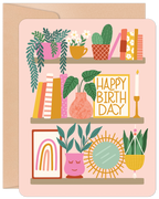 Cute plant shelf greeting card featuring potted greenery, books, a 'HAPPY BIRTHDAY' sign, and bohemian decor on a soft pink background. Ideal for plant lovers.