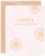 Heartfelt floral birthday card for Mom featuring 'Mom you are so loved' text in elegant gold, delicate white and gold outline flowers on a soft pink background, with a natural kraft envelope. Perfect for celebrating a mother's special day.