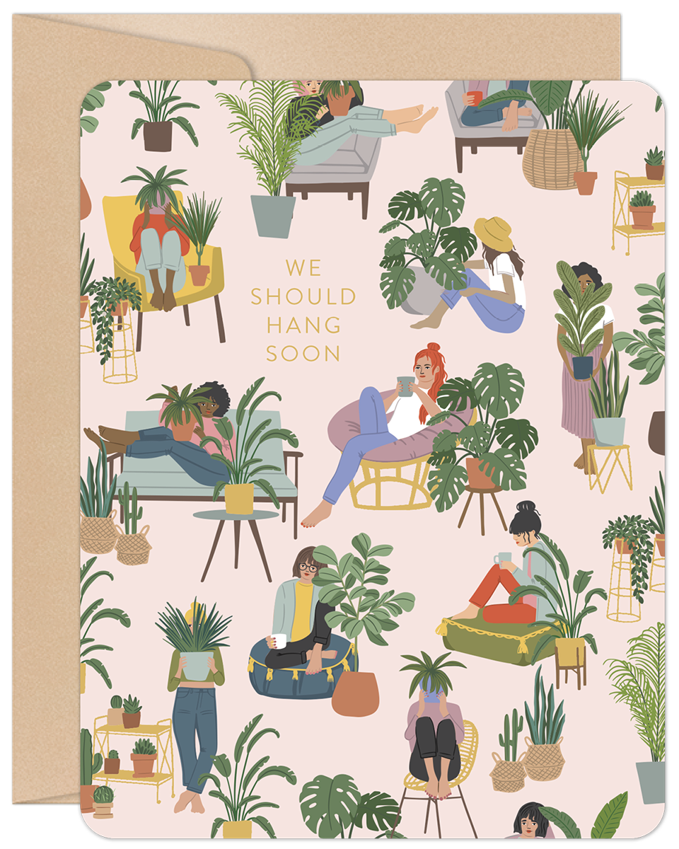 Charming friendship card front with diverse women relaxing among houseplants on pink. Text: 'We Should Hang Soon'. Perfect for plant lovers.