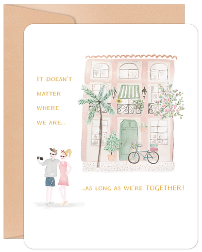 Front of 'Home Is Wherever' anniversary card, featuring a charming pink house watercolor and a couple taking a selfie, with heartfelt text.