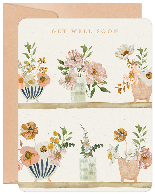 Get Well Soon card featuring watercolor floral arrangements in various vases on two rustic shelves, with a soft peach envelope.