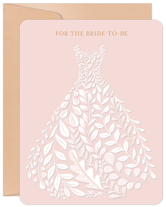 Elegant bride-to-be engagement card with a botanical vine wedding dress illustration on a blush pink background, next to a kraft envelope.