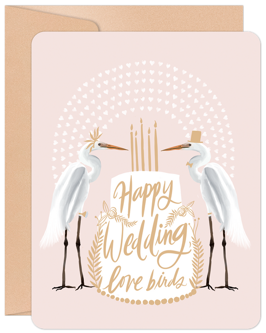 Happy Wedding Love Birds greeting card featuring two egrets dressed as bride and groom with a wedding cake, on a pink background.