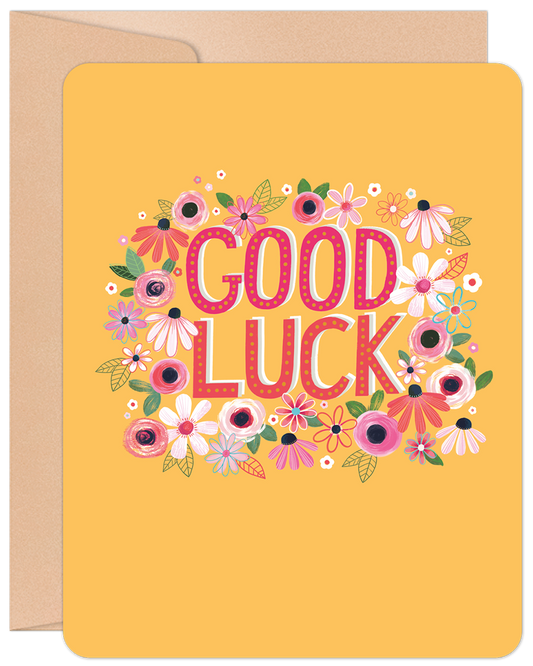 Front of a vibrant good luck greeting card with 'GOOD LUCK' in pink letters surrounded by a cheerful floral border on a yellow background.