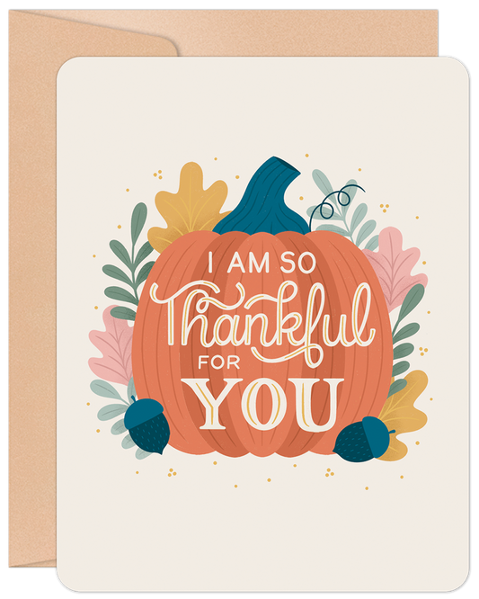 Front of a 'Thankful for You Pumpkin' greeting card with a vibrant pumpkin illustration and fall leaves on a cream background, with a kraft envelope visible.