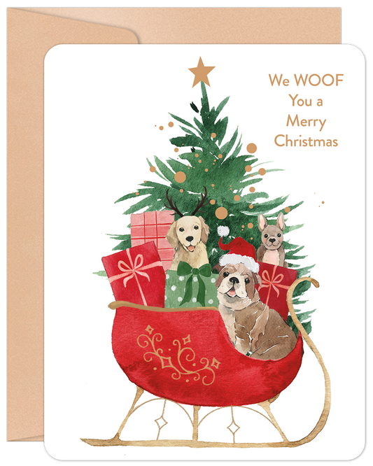 Front of Christmas card: three cute dogs in a red Santa's sleigh with a tree and gifts. Text: We WOOF You a Merry Christmas.