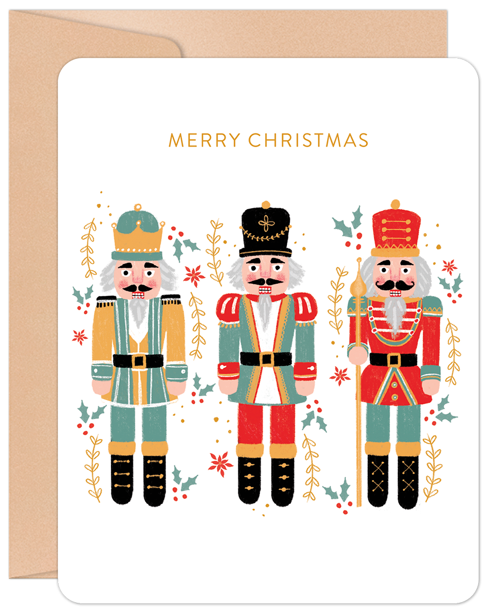 Front of a festive Christmas card featuring three colorful nutcrackers, holly, and berries, with 'MERRY CHRISTMAS' in gold.