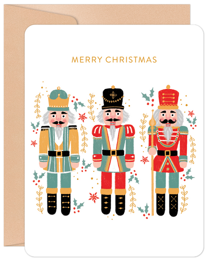 Front of a festive Christmas card featuring three colorful nutcrackers, holly, and berries, with 'MERRY CHRISTMAS' in gold.