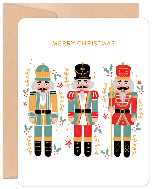 Front of a festive Christmas card featuring three colorful nutcrackers, holly, and berries, with 'MERRY CHRISTMAS' in gold.