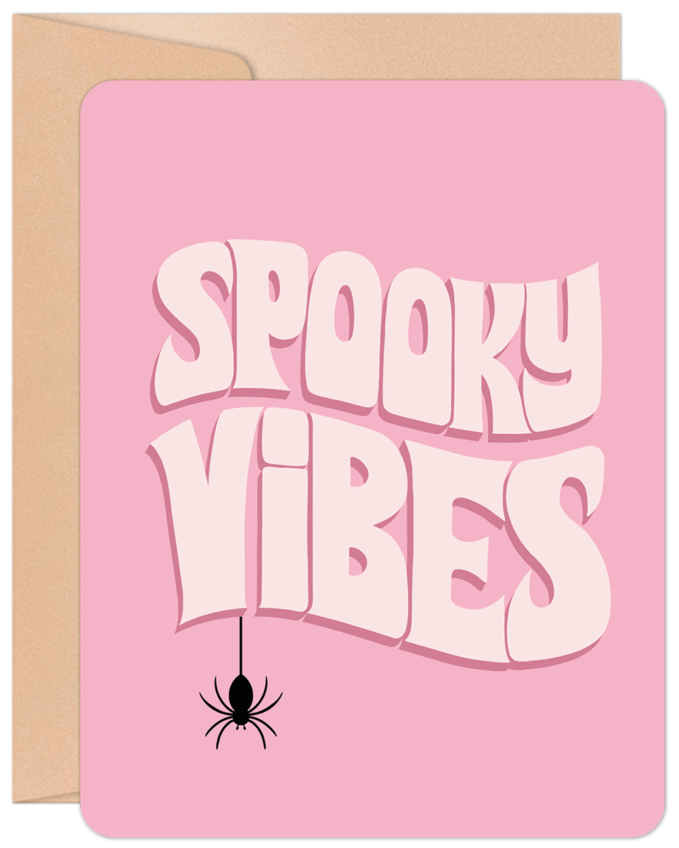 Pink Halloween greeting card featuring "Spooky Vibes" text in white and a black spider, resting on a brown kraft envelope.
