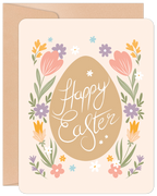 Front of a cute Easter greeting card featuring a central brown egg with 'Happy Easter' in white script, framed by colorful floral elements including pink tulips, yellow and purple flowers, and green leaves. A kraft paper envelope is visible behind the card.