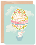 Whimsical bunny in floral egg hot air balloon greeting card, light blue sky with clouds, perfect for springtime celebrations and children.