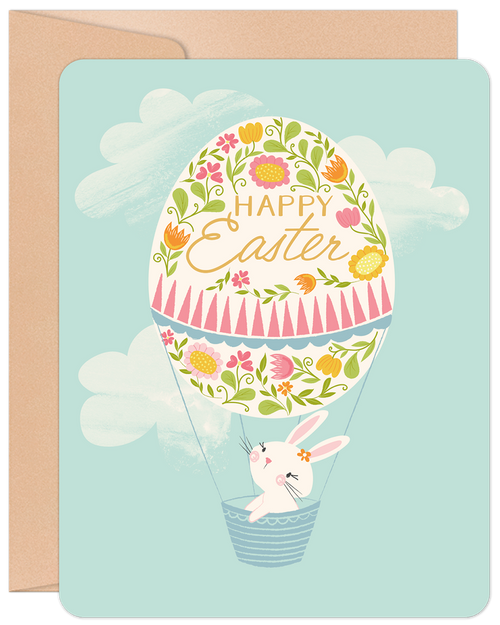 Front of a cute Easter greeting card featuring an adorable white bunny in a hot air balloon shaped like a decorated floral egg, against a light blue sky with white clouds. 'Happy Easter' is written on the egg.