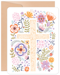 Front of a religious Easter greeting card featuring a wooden cross adorned with a vibrant array of purple, orange, pink, and yellow spring flowers, green leaves, and decorative pastel eggs. A brown kraft envelope is visible in the background, hinting at the high-quality stationery.