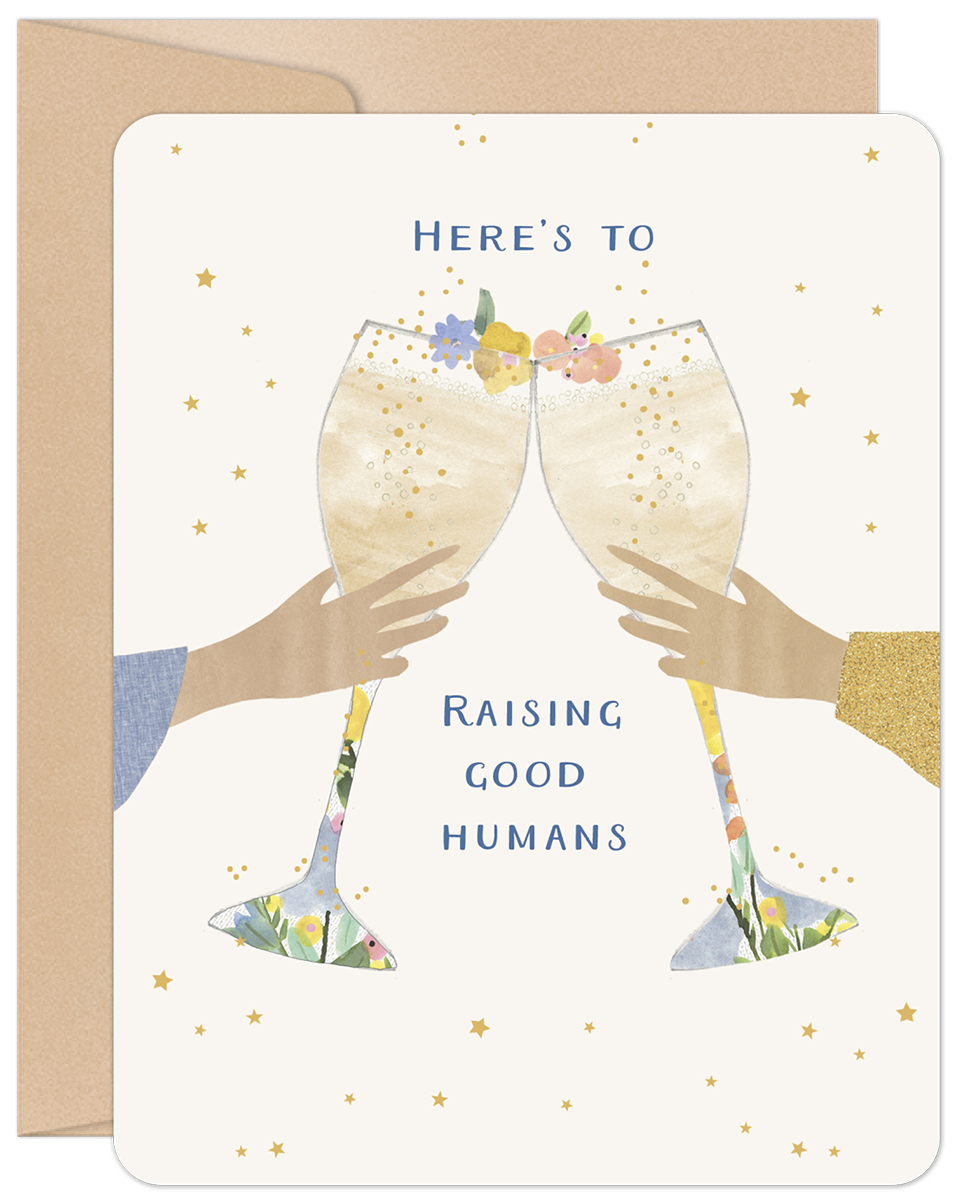 Front view of a cream-colored greeting card featuring two hands holding champagne flutes in a celebratory toast, adorned with delicate floral details and scattered gold stars. The text reads "HERE'S TO RAISING GOOD HUMANS".