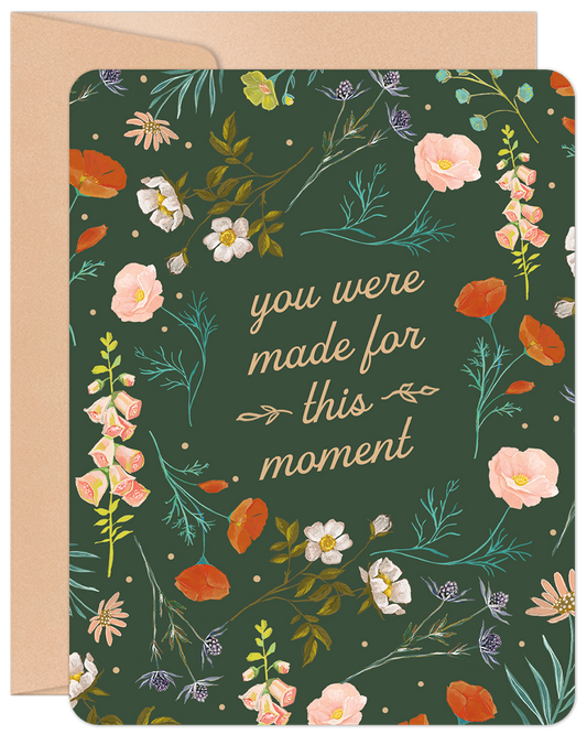 Front of a dark green graduation card with a floral border and 'you were made for this moment' in white script.