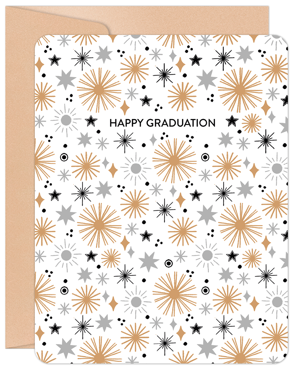 Front view of an inspiring graduation greeting card featuring gold, silver, and black starbursts on a white background, next to a kraft paper envelope. The card reads 'HAPPY GRADUATION'.