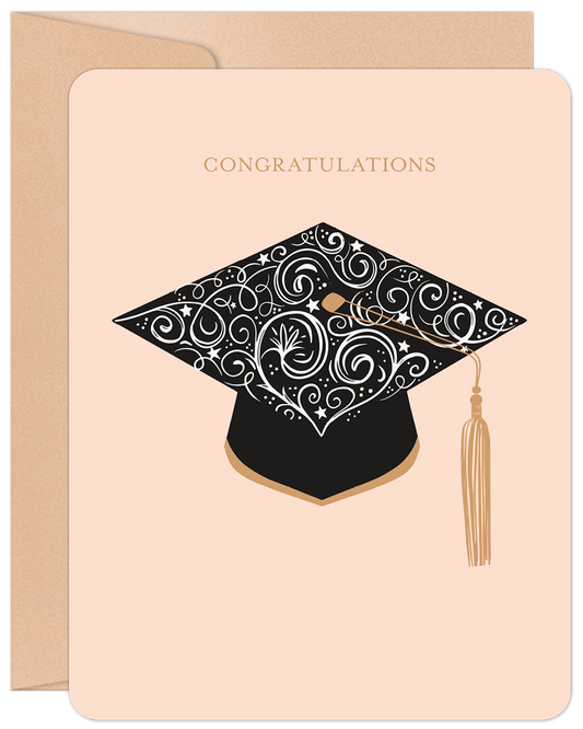 Elegant graduation card featuring a black and gold cap with intricate swirl designs and a 'CONGRATULATIONS' message on a light pink background.