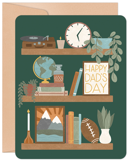 Front of 'Happy Dad's Day' greeting card featuring three shelves with a record player, globe, books, football, plants, clock, and candles on a dark green background.