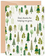 Front of a Father's Day greeting card featuring a whimsical forest of green evergreen and deciduous trees on a cream background. The text reads 'Dad, thanks for helping me grow.' A rustic kraft paper envelope is visible behind the card.