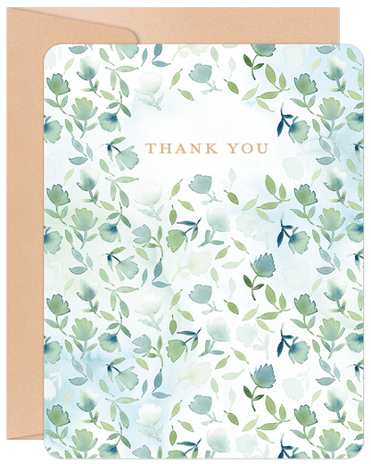 Front of a 'Thank You' greeting card with watercolor green and blue floral design, accompanied by a kraft envelope.