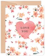 Front view of a romantic watercolor greeting card featuring a large pink heart with 'LOVE YOU' text, surrounded by soft peach and pink floral blossoms. A kraft paper envelope is visible behind the card.