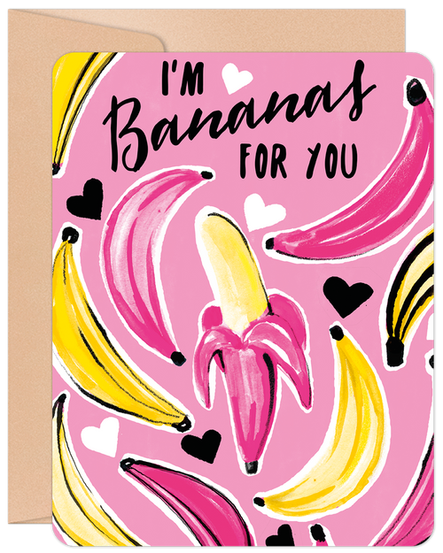 Front of a playful Valentine's Day greeting card with a bright pink background. It features multiple vibrant yellow and pink bananas, some partially peeled, and scattered white and black hearts. The text in a whimsical script font reads: "I'm Bananas FOR YOU". The card is shown with a brown kraft envelope.