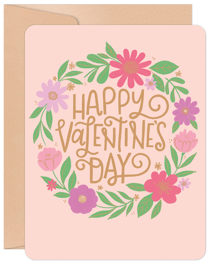Happy Valentine's Day floral wreath greeting card with pink, purple, and green flowers on a light pink background, includes an envelope.