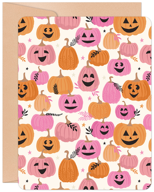 Front of a cute Halloween greeting card featuring a pattern of smiling pink and orange pumpkins with small leaves and stars.