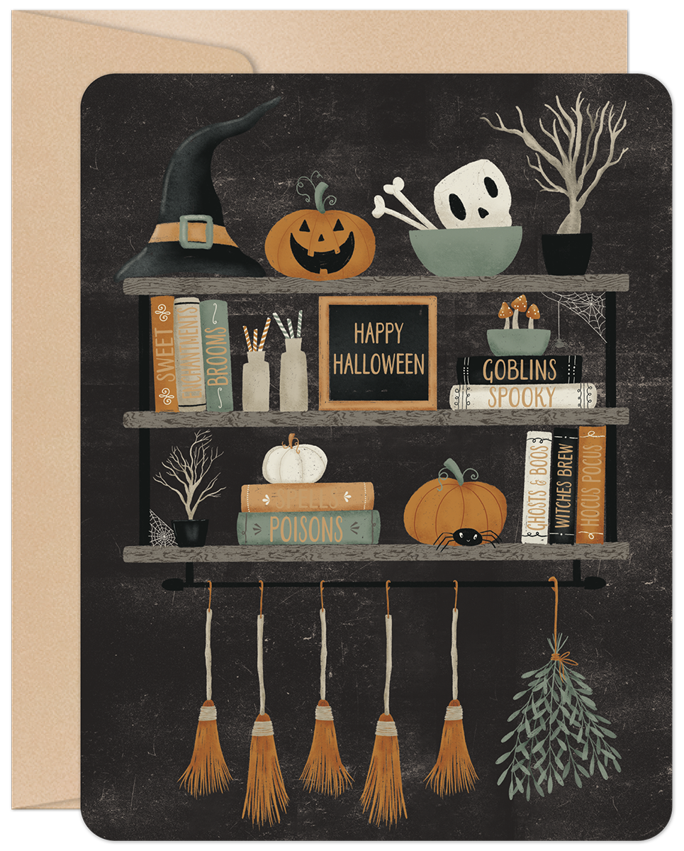 Front of a charming Halloween greeting card featuring a witch's hat, carved pumpkins, a skull, and magic books on rustic shelves.
