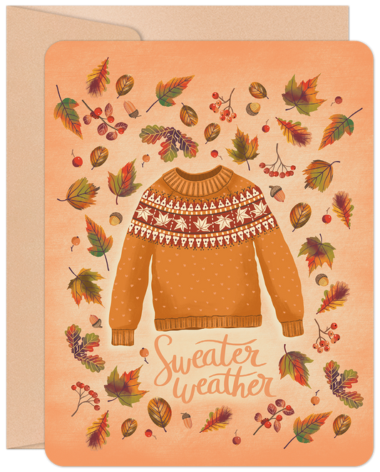 Front of a cozy fall greeting card with an orange sweater, fair isle pattern, surrounded by colorful autumn leaves, acorns, and berries. Text says 'Sweater weather'.