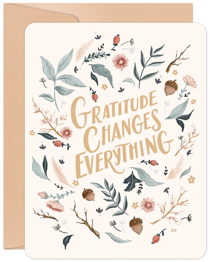 Front of a gratitude greeting card with "Gratitude Changes Everything" surrounded by floral and botanical illustrations, with a kraft envelope.