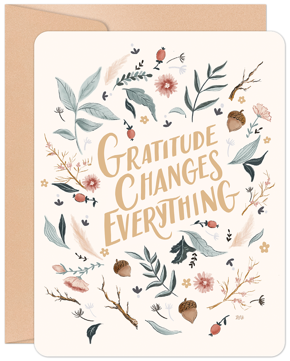 Front of a heartfelt Thanksgiving greeting card with 'Gratitude Changes Everything' in elegant calligraphy, surrounded by an autumn wreath of botanical leaves, acorns, and berries, presented with a neutral kraft envelope.