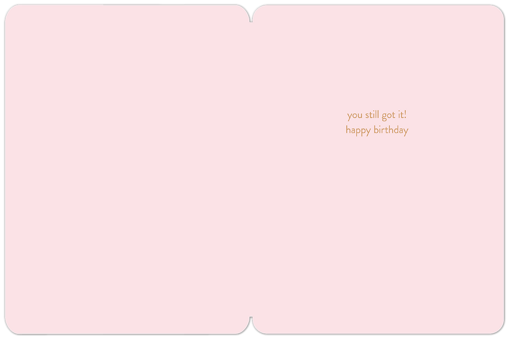 Open view of a light pink interior of a playful birthday card, showing a subtle message in elegant gold script: 'you still got it! happy birthday' with ample space for a personal handwritten note.