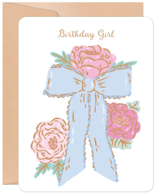 Front of a white birthday greeting card featuring 'Birthday Girl' in elegant gold script, adorned with three delicate pink watercolor roses and a large ruffled light blue bow, presented against a warm kraft paper envelope background.