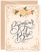 Elegant greeting card for a new arrival featuring 'Bonjour, Bébé' in sophisticated calligraphy, adorned with soft peach roses and gold botanical details, paired with a kraft envelope. Perfect for welcoming a little one.