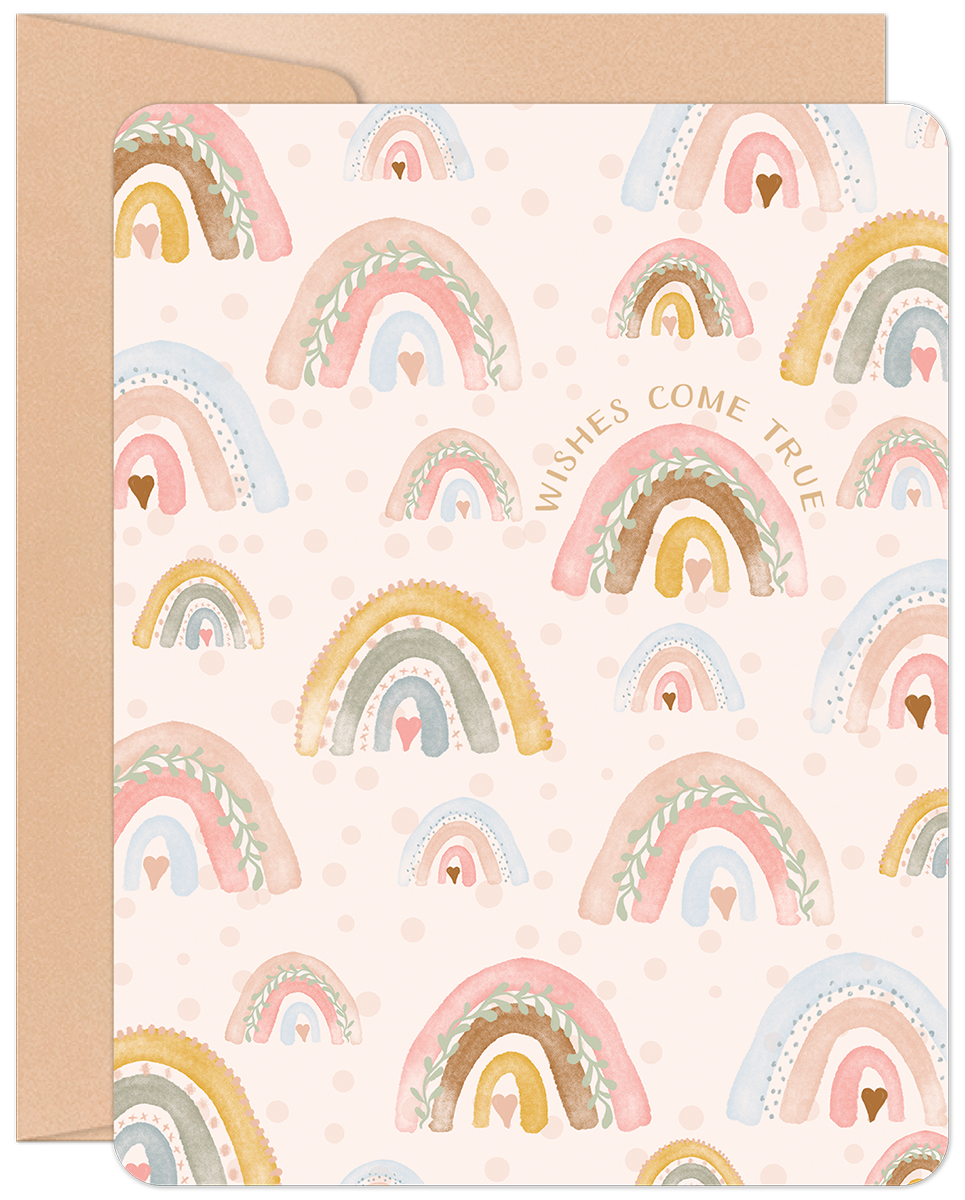 Cute new baby greeting card with watercolor rainbows, hearts, and "Wishes Come True" text, on a craft paper envelope.